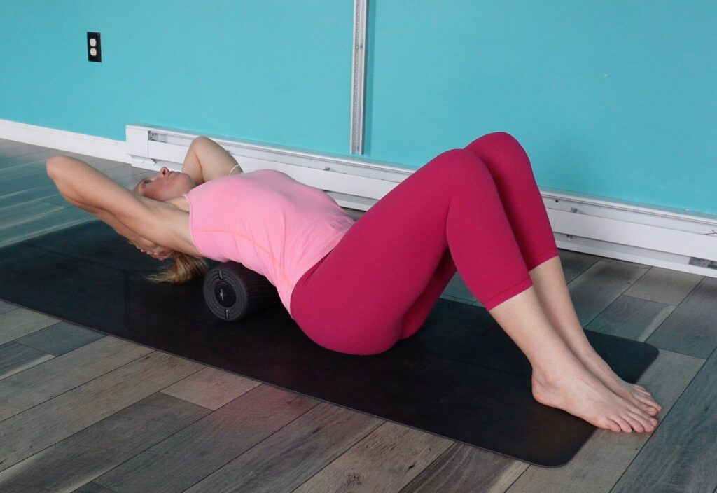 Dr. Chloe with a foam roller under her middle back, hands clasped behind her head arching back to improve her thoracic spine mobility